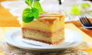 Kawałek tortu z warstwami ciasta, kremu i dżemu, ozdobiony miętą.