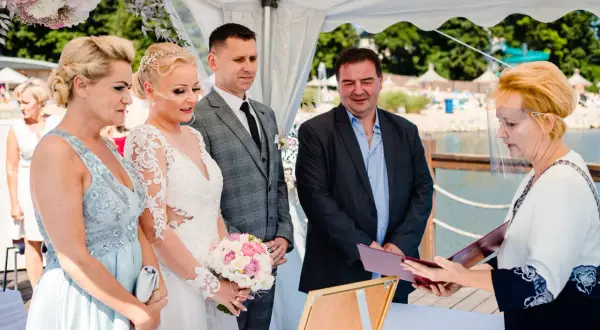 Ślub cywilny nad jeziorem: para młoda, świadkowie i urzędniczka w przyłbicy.